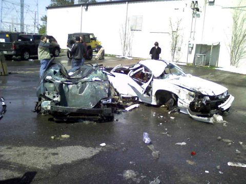 Two heavily damaged cars, one white and one green, in a lot