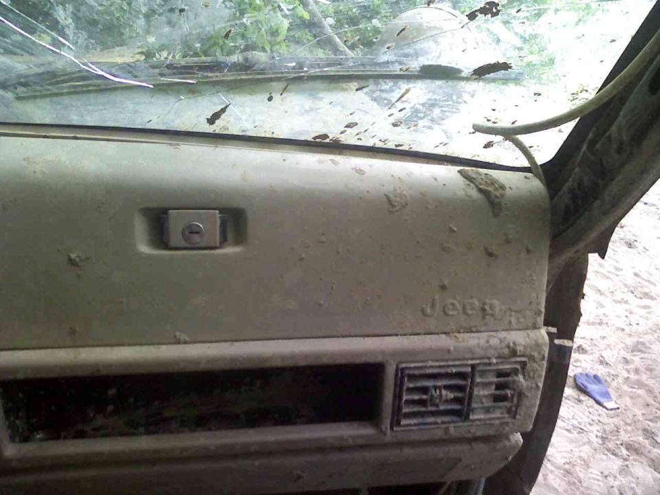 Jeep dashboard with glove box lock and air vent. Text 'Jeep' is visible