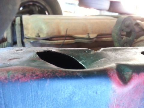 1991 Ford Festiva - A damaged metal car part is shown with a hole in its surface.