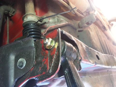 1991 Ford Festiva - Undercarriage view of a vehicle's suspension system, focusing on a metal bracket and bolt.