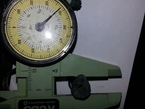 1994 Ford Bronco - A dial indicator and caliper are used to measure a small automotive part.