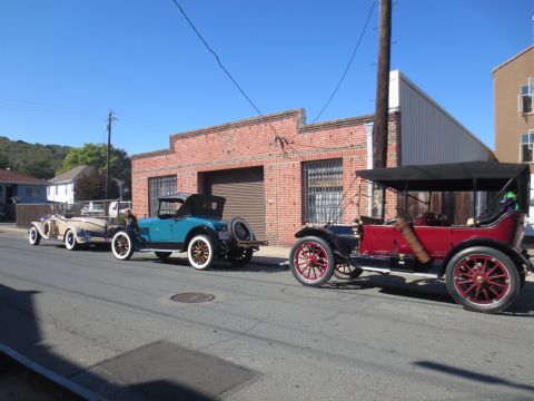 1946 Jeep CJ5 - A line of vintage automobiles are parked on a street in front of a brick building.