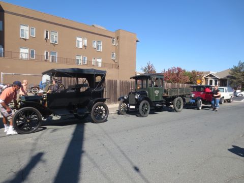 1946 Jeep CJ5 - A line of vintage vehicles, including a black touring car and two trucks, participate in a drive.