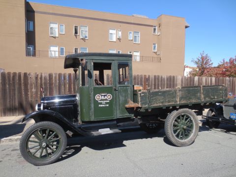 1946 Jeep CJ5 - A vintage flatbed truck with a green cab and wooden bed is parked on a street.
