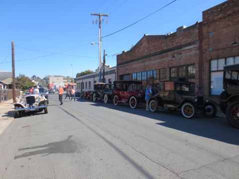 1946 Jeep CJ5 - A collection of vintage automobiles are lined up along a street next to a brick building.