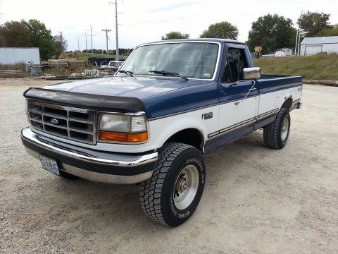 1994 Ford F-250 - This 1994 Ford F-250 pickup truck is shown from a three-quarter front angle, highlighting its two-tone paint scheme and chrome accents.