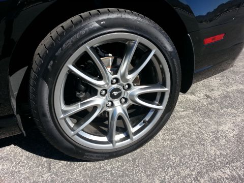 2013 Ford Mustang - A close-up view of the wheel and tire assembly on a black Ford Mustang, highlighting the vehicle's design details.