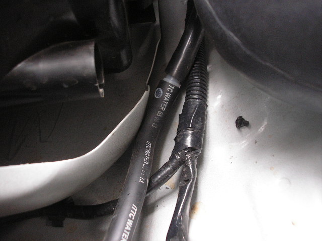 Close-up of black hoses and wiring with "TC WATER 05.06.13" text, inside a vehicle
