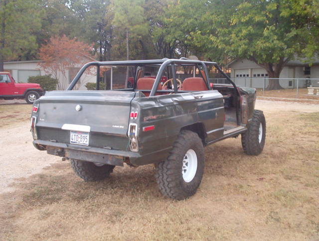 Dark green 1982 Jeep Wagoneer with roll cage and off-road tires, rear view