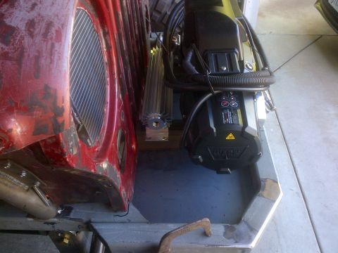 1985 Jeep CJ7 - A winch and oil cooler are installed in the engine bay of a red Jeep CJ-series vehicle.