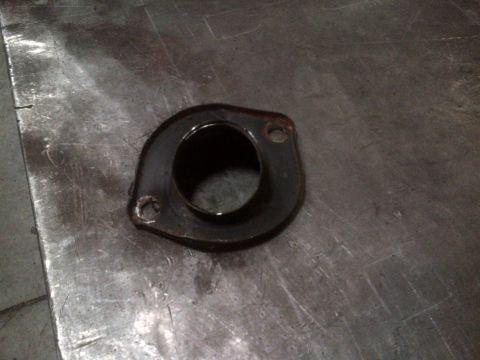 1985 Jeep CJ7 - A metal exhaust flange rests on a textured surface, showing signs of wear and use.