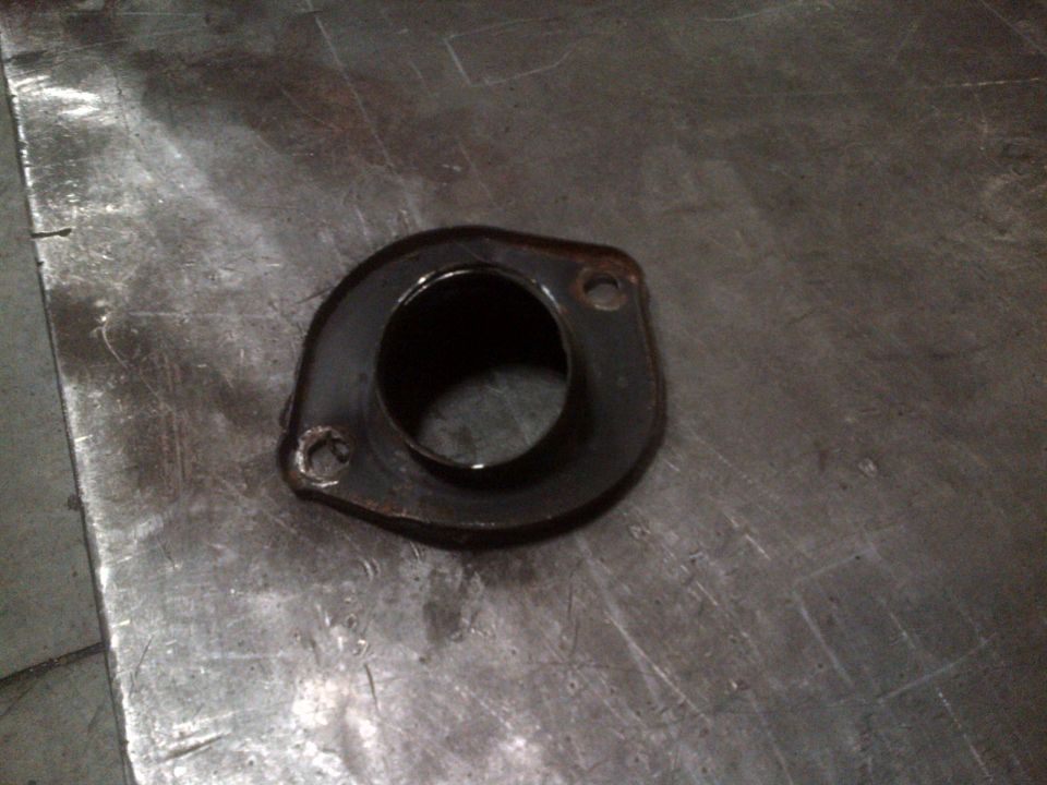 Exhaust flange with two bolt holes on a metal surface