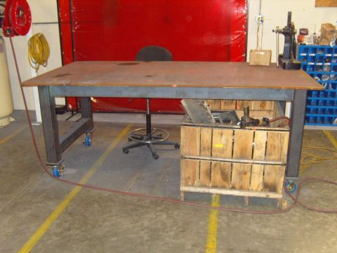 1985 Jeep CJ7 - A workbench with a metal top and storage crates sits in a workshop setting.
