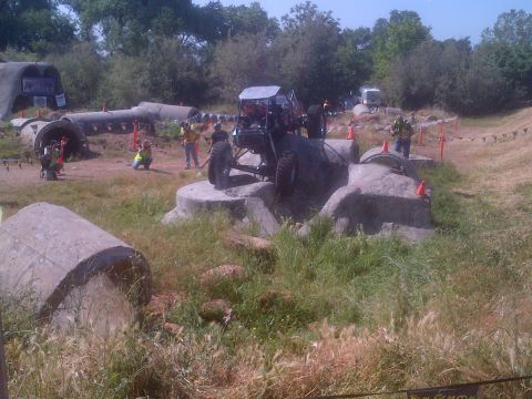 1985 Jeep CJ7 - An off-road buggy maneuvers through a challenging obstacle course with spectators and other vehicles present.