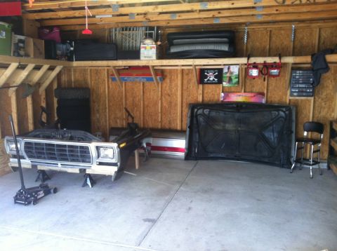 1979 Ford Bronco - The front clip of a 1979 Ford Bronco is disassembled and supported by jack stands in a garage.