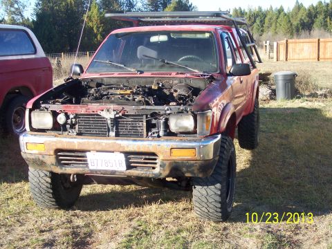 1991 Toyota Pickup/SR5 - A red 1991 Toyota Pickup SR5 is parked outdoors with its hood open, showing the engine compartment.