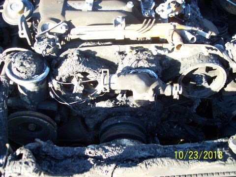 1991 Toyota Pickup/SR5 - The engine bay of a vehicle shows extensive fire damage, with charred components and melted debris obscuring most details.