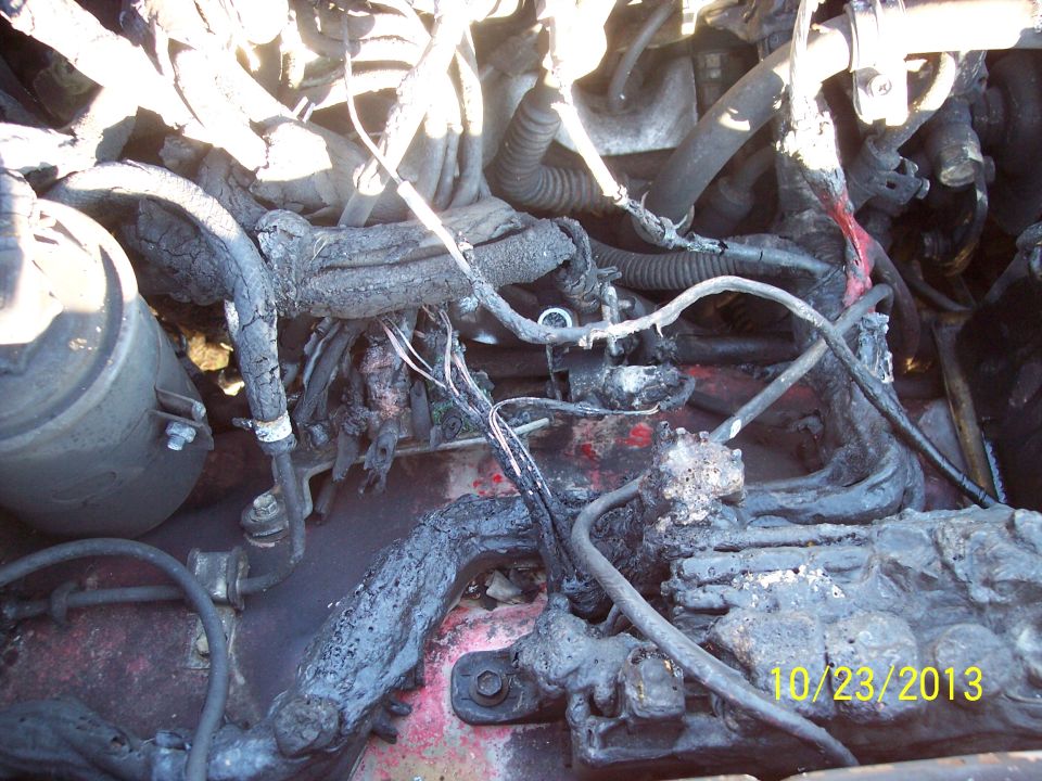 Engine bay with melted and burnt wiring harness. Date stamp 10/23/2013