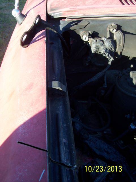 1991 Toyota Pickup/SR5 - Close-up of a black metal bracket on a red vehicle's fender, with engine bay details.