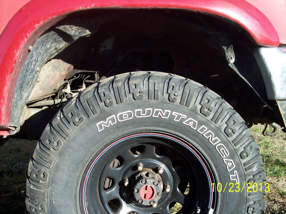 Red truck fender and tire with 'MOUNTAIN CAT' text visible