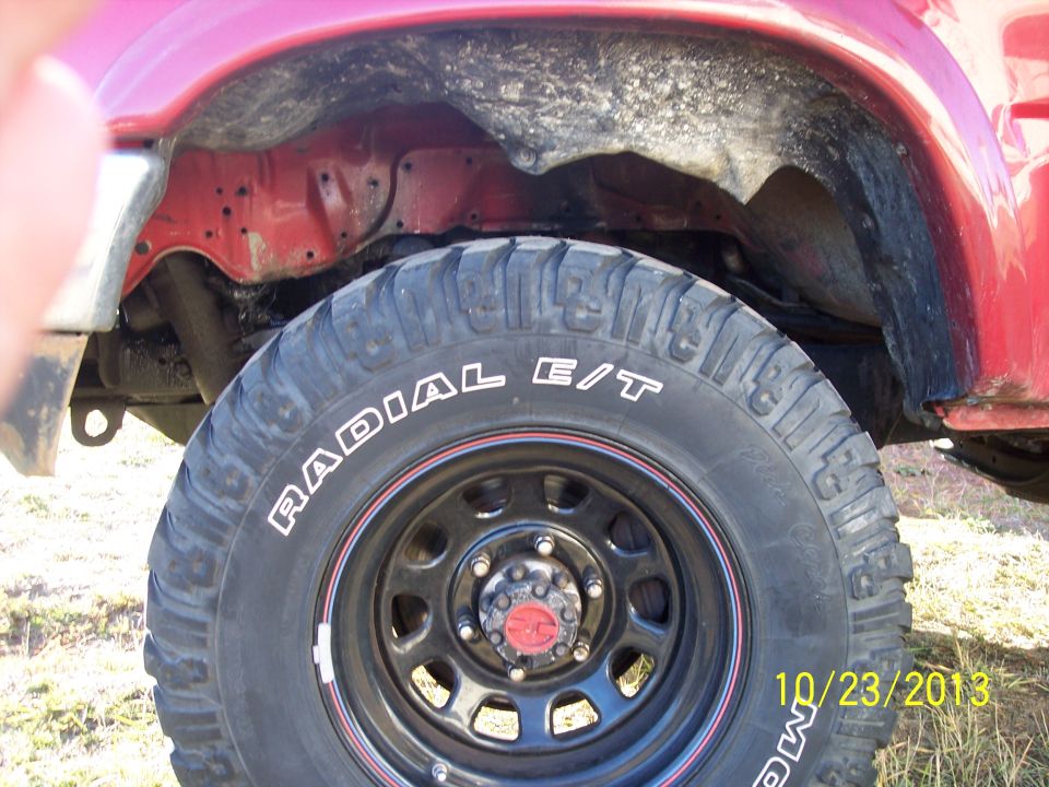 Close-up of a red vehicle's wheel well and a Radial E/T tire on a black rim. Date stamp reads 10/23/2013