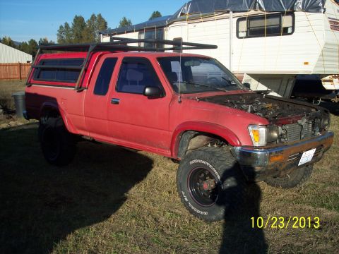 1991 Toyota Pickup/SR5 - Red 1991 Toyota Pickup/SR5 with camper shell and roof rack parked outdoors.