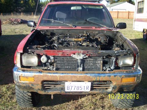1991 Toyota Pickup/SR5 - This red pickup truck has its hood open, revealing a damaged engine compartment and a rusty front end.