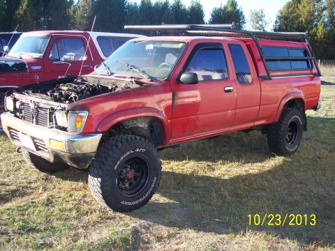 1991 Toyota Pickup/SR5 - A red 1991 Toyota Pickup SR5 is parked outdoors with its hood up, next to another vehicle.