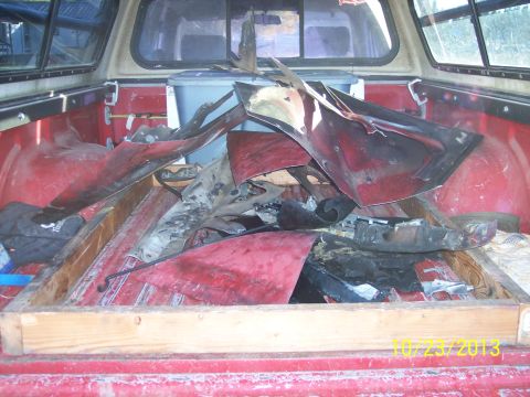 1991 Toyota Pickup/SR5 - A collection of damaged red car body panels are loaded into the bed of a pickup truck.