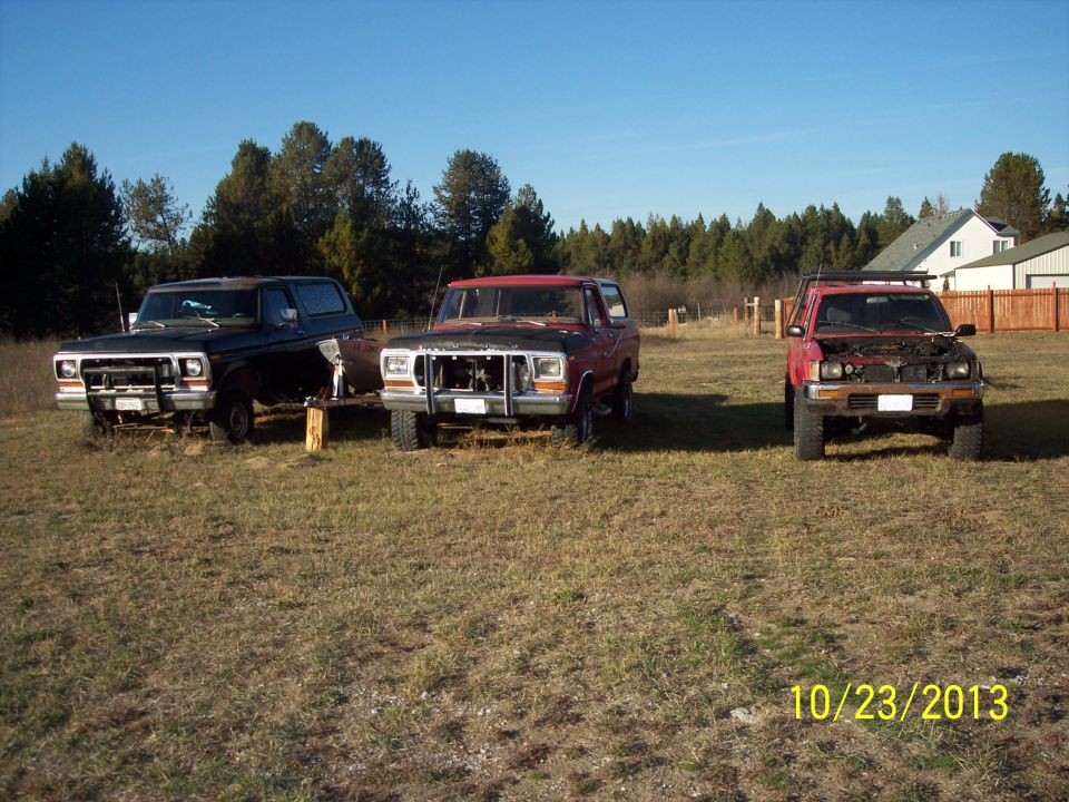 Three trucks parked in a grassy field under a clear blue sky