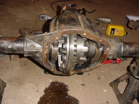 1992 Ford Bronco - Close-up of a differential axle assembly, showing internal gears and surrounding tools on a workshop floor.