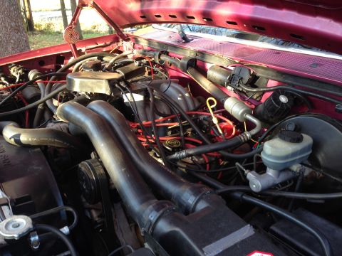 1992 Ford F-150 - Close-up view of the engine compartment in a red Ford truck, highlighting the V8 engine and associated components.