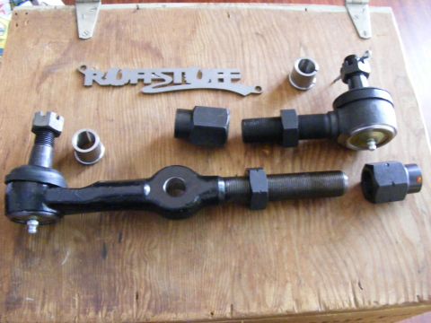 Steering linkage parts including tie rod ends and sleeves on a wooden surface