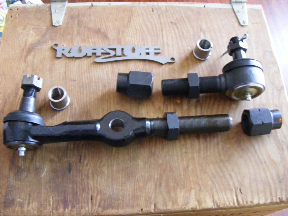 Steering linkage parts including tie rod ends and sleeves on a wooden surface