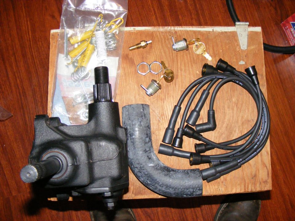 Steering gear box, spark plug wires, keys, and springs on a wooden board