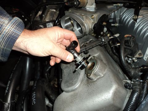 2004 Mercury Grand Marquis - Close-up of a hand manipulating a part on an engine, with visible hoses and wiring.