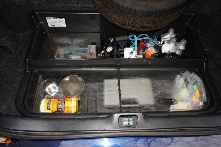 Trunk organizer with spare tire, oil bottles, and cleaning supplies