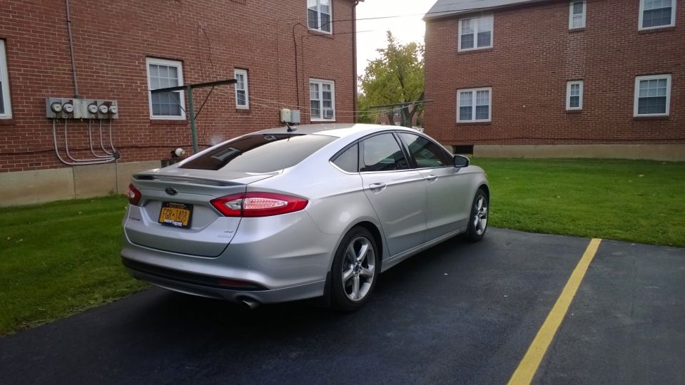 Silver sedan parked in a lot next to a brick building