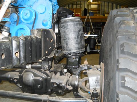 1992 Ford Bronco - Close-up view of a vehicle's front suspension system, an air bag and a portion of a large tire.