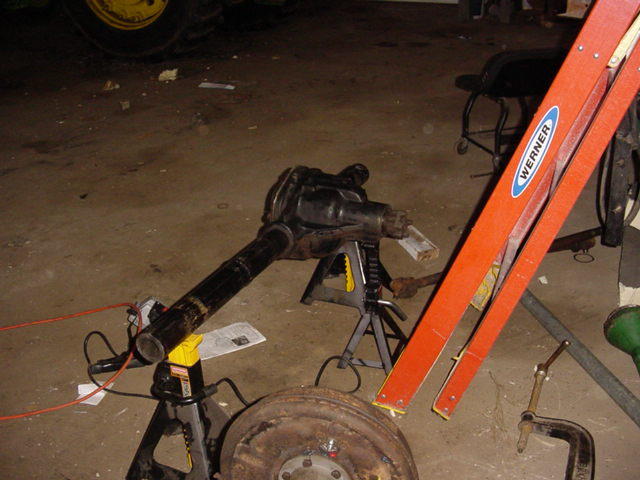 Front axle assembly on jack stands with a Werner ladder nearby