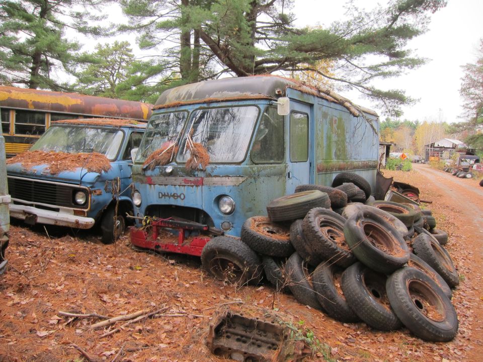 Blue step van with DH460 on front, next to another van and a bus