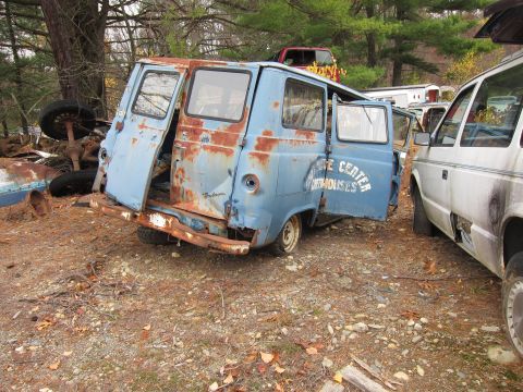 1991 Ford LTD Crown Victoria - A dilapidated blue van sits in a junkyard next to a white minivan.