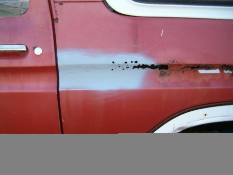 1979 Ford Bronco - Side view of a 1979 Ford Bronco door with rust and body filler visible.