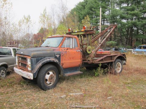 1991 Ford LTD Crown Victoria - A weathered tow truck sits among other vehicles in an outdoor storage area.