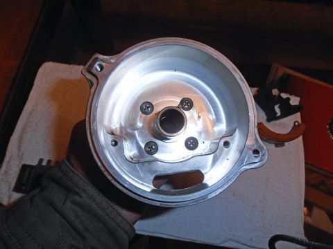 1990 Ford Bronco - A person holds a clean metal distributor housing, showing its internal screw mounts and central shaft opening.