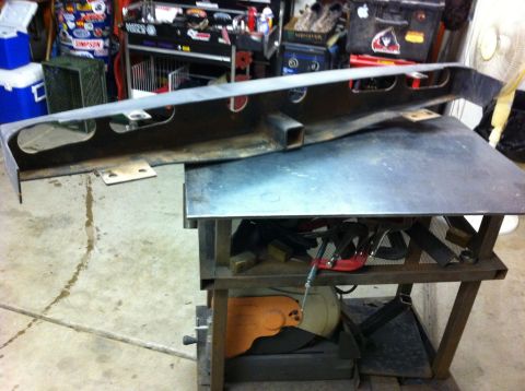 1987 Suzuki Samurai - A metal rear bumper with a square receiver hitch mount is shown on a workbench.