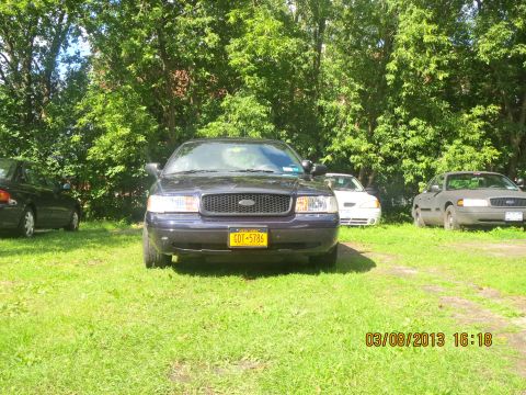 2003 Ford Crown Victoria - Front view of a 2003 Ford Crown Victoria, parked outdoors with other vehicles visible.
