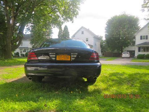 2003 Ford Crown Victoria - Rear view of a black 2003 Ford Crown Victoria parked on a grassy lawn with houses in the background.