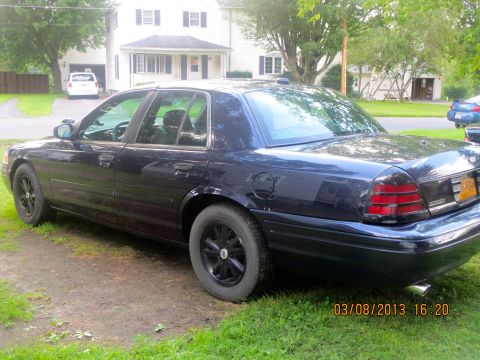 2003 Ford Crown Victoria - A dark blue 2003 Ford Crown Victoria is parked on a grassy area next to a driveway.