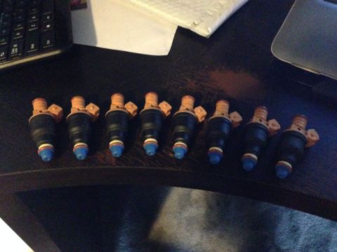 1992 Ford F-150 - A set of eight fuel injectors are laid out on a dark surface, likely for a vehicle repair or upgrade.